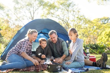 Family roasting marshmallows outside the tent