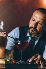 Barman is making cocktail at night club.