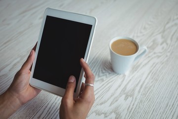 Hands of woman holding digital tablet by coffee 