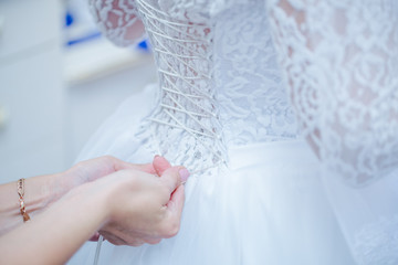 Невесте затягивают корсет.