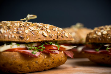 Sandwich with cereal bread, ham, tomatoes and cress on the dark background. Selective focus. 