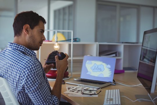 Photographer holding camera while sitting in creative office