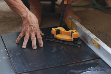 Ceramic Tiles. Tiler placing ceramic wall tile in position over adhesive with lash tile leveling system