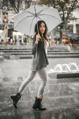 Woman with an umbrella under rain on a city street