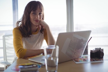 Portrait of young businesswoman sitting at office desk