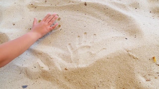 Closeup of tanned human hands of family of two persons. Mother and little son making handprints in sand on river beach. Togetherness concept. Real time full hd video footage.