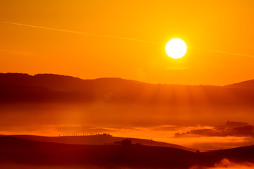 Golden sunrise over the misty fields in Tuscany, Italy