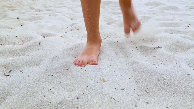 Closeup of legs of little child. Kid  walks towards to camera first then stops, turns around and walk away from camera. Sandy river beach. Real time full hd video footage.