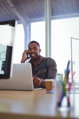 Fototapeta premium Smiling businessman talking on phone in creative office