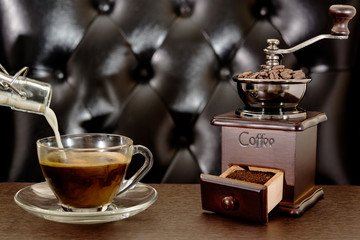 Old coffee grinder and coffee cup on wooden table. Latte coffee