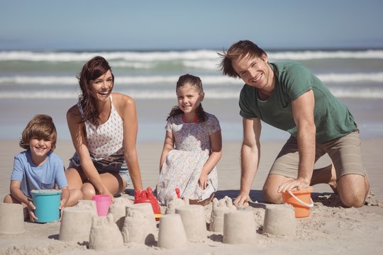 Portrait Of Happy Family Making Sand Castle At Beach