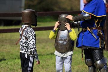 Dwaj mali chłopcy ubierają się w zbroje rycerskie.