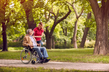 senior man in wheelchair in the park with daughter.