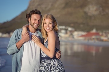Naklejka premium Portrait of happy young couple embracing at beach