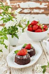 Chocolate fondant lava cake with strawberries, mint and powdered sugar.vertical