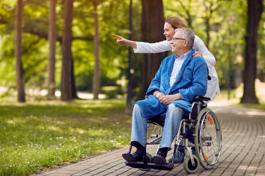 nurse showing something to elderly man on wheelchair..