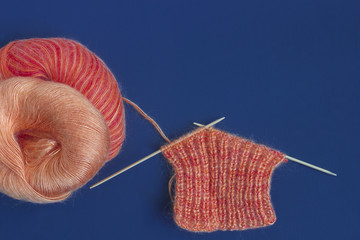 Knitting needles and orange multicolor colorful mohair soft warm winter yarn ball on dark wooden...
