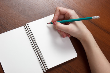 Closeup photo of girl writing in notebook with pencil