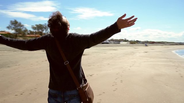 Camera moving around man on beach feeling free and happy steadycam shot