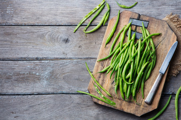 Green beans on wooden cutting board. Top view