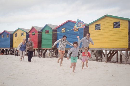 Happy multi-generation family running by beach huts at beach