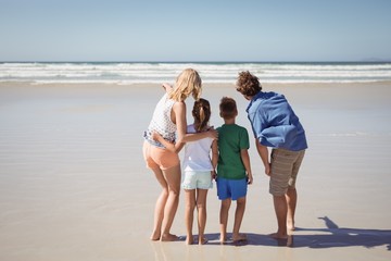 Rear view of family standing together at beach