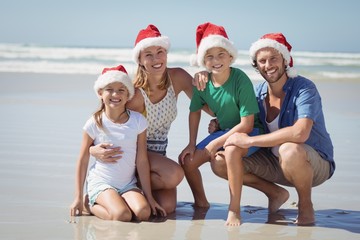 Portrait of smiling family wearing Santa hat at beach