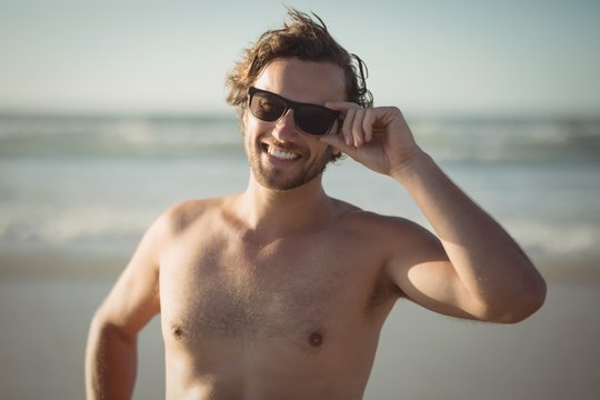 Portrait Of Shirtless Man Wearing Sunglasses At Beach