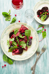 Homemade pink ravioli (tortellini) with goat cheese decorated beet leaves, beetroot slices and cranberry on wooden table. Selective focus