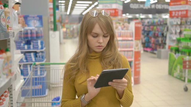 Woman in supermarket checking shopping list on tablet