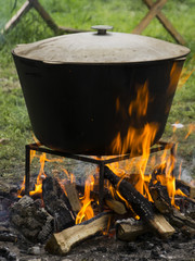 Food in a cauldron on a fire. Cooking outdoors in cast-iron cauldron.