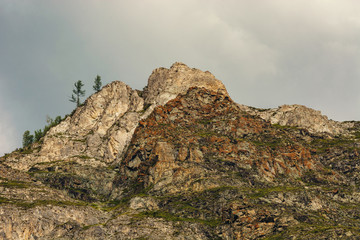 The rocks on the background of cloudy sky. Lichen on the rocks. Spruce.