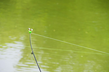 fishing pole with bells in the green calm river, bottom fishing line