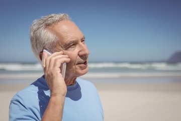 Senior man talking on mobile phone at beach