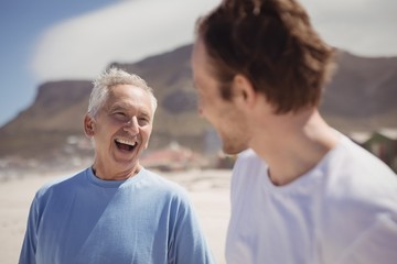 Obraz premium Cheerful senior man with his son standing at beach