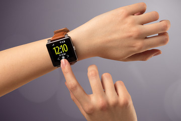 Female hand wearing and pressing smartwatch