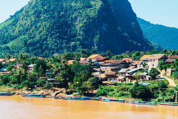 Colorful landscape of Nong Khiaw and orange-yellow muddy Ou river with local boats, Laos