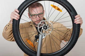 Bearded man puts the front wheel on the bicycle.