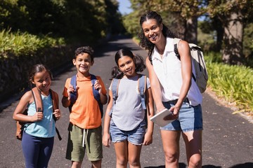 Obraz premium Portrait of happy teacher and students with tablet PC on street