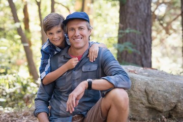 Smiling father and son hiking in forest