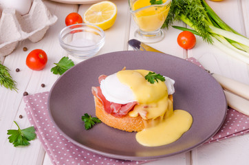 Eggs Benedict for breakfast on white wooden background