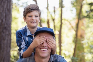 Portrait of boy covering fathers eyes 