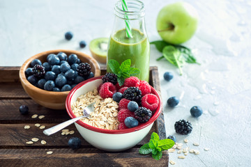 Muesli with berries and green smoothie bottle, fresh healthy breakfast, vegan, diet and detox...