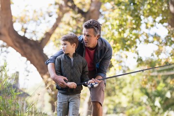 Father and son fishing in forest 