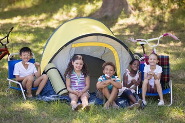 Fototapeta na wymiar Cheerful children sitting outside tent at campsite