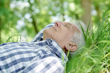 Senior man taking a nap laying down in grass