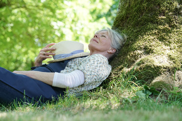 Senior woman relaxing in garden by tree