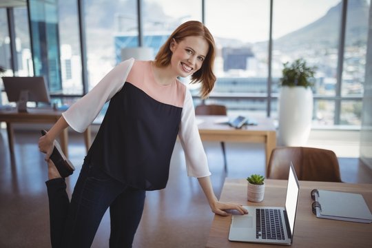 Portrait of smiling executive using laptop while exercising