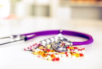 Close up of pills spread over the table with stethoscope and heart lying beside