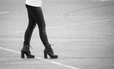 Fototapeta premium Legs of a girl in black pantyhose walking along the road